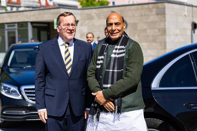 Boris Pistorius standing beside India's Defence Minister Rajnath Singh outdoors next to dark official cars