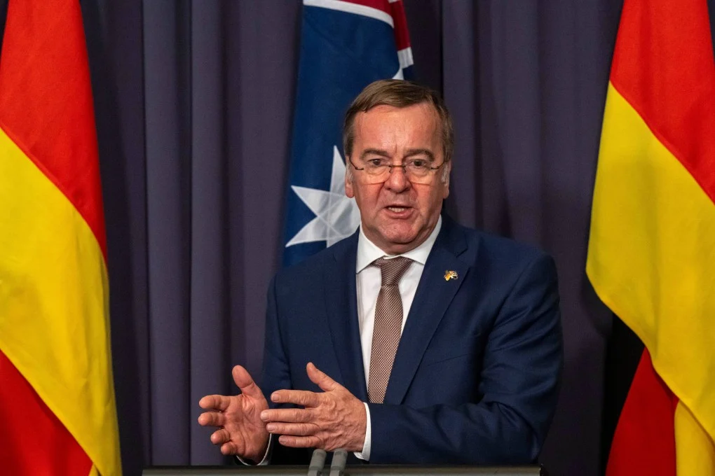 Boris Pistorius speaking at a press conference between German and Australian flags