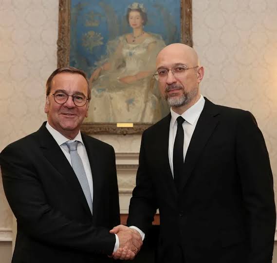 Boris Pistorius shaking hands with Ukraine's Denys Shmyhal in a formal room beneath a portrait painting